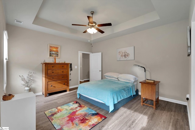 bedroom featuring ceiling fan, a raised ceiling, and hardwood / wood-style floors