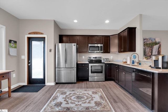 kitchen with stainless steel appliances, sink, light hardwood / wood-style floors, and dark brown cabinets