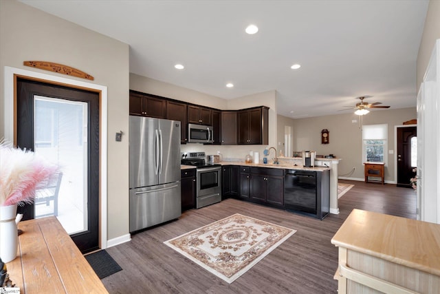 kitchen featuring dark brown cabinetry, sink, appliances with stainless steel finishes, dark hardwood / wood-style flooring, and kitchen peninsula