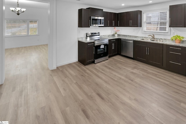 kitchen featuring decorative light fixtures, appliances with stainless steel finishes, sink, and light hardwood / wood-style flooring