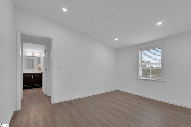 unfurnished bedroom with lofted ceiling, ensuite bathroom, and light hardwood / wood-style flooring