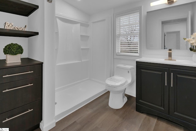 bathroom with vanity, toilet, hardwood / wood-style floors, and a shower