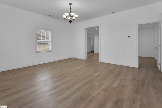 unfurnished room with an inviting chandelier and light wood-type flooring