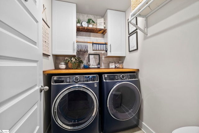 clothes washing area featuring cabinets and washer and dryer