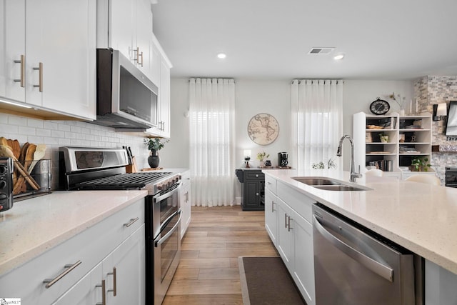 kitchen with white cabinetry, sink, light stone counters, and appliances with stainless steel finishes