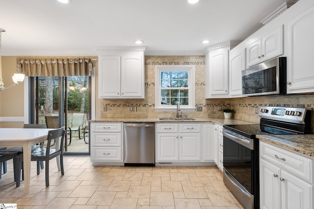 kitchen with appliances with stainless steel finishes, light stone countertops, sink, and white cabinets