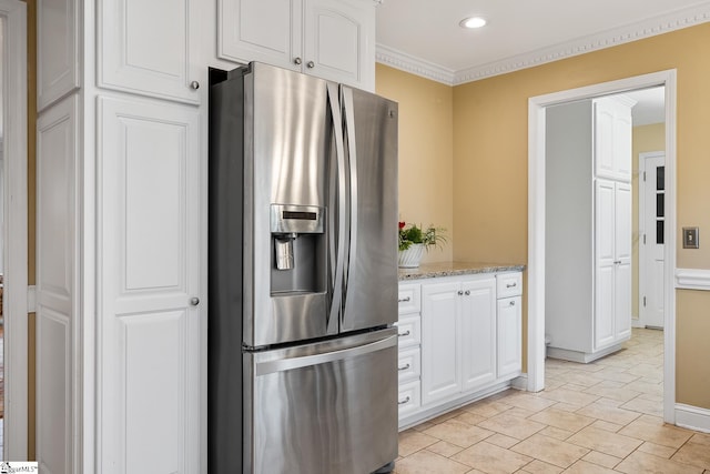 kitchen featuring white cabinetry, ornamental molding, light stone countertops, and stainless steel refrigerator with ice dispenser