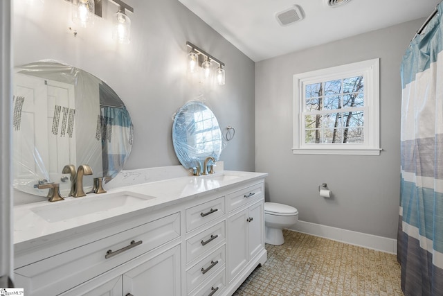 bathroom with tile patterned floors, vanity, toilet, and a wealth of natural light