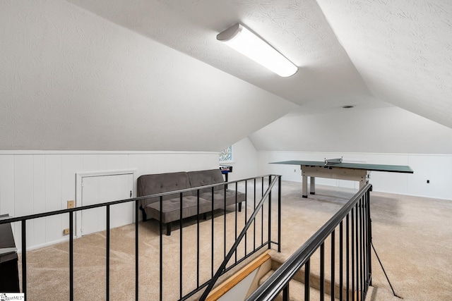 hallway with vaulted ceiling, a textured ceiling, and carpet flooring