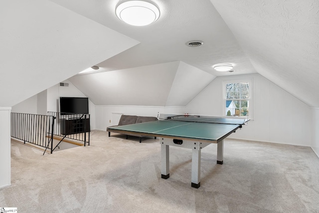 rec room featuring light carpet, vaulted ceiling, and a textured ceiling