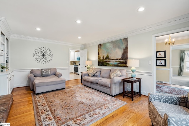 living room with ornamental molding, a chandelier, and light hardwood / wood-style flooring