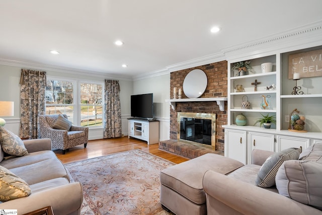 living room featuring ornamental molding, a fireplace, and light hardwood / wood-style floors