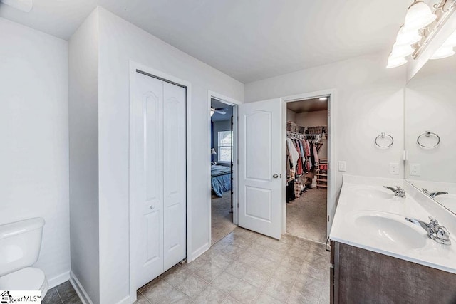 full bathroom featuring a sink, double vanity, toilet, and a closet