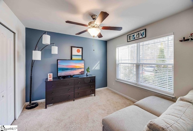 interior space with baseboards, a ceiling fan, and light colored carpet