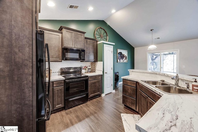 kitchen with lofted ceiling, a sink, light countertops, black appliances, and pendant lighting