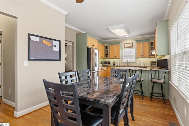 dining space featuring ornamental molding, sink, and light hardwood / wood-style flooring