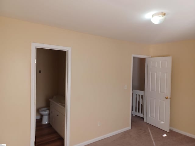 unfurnished bedroom featuring ensuite bath and carpet floors