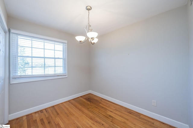 empty room featuring hardwood / wood-style flooring and a chandelier