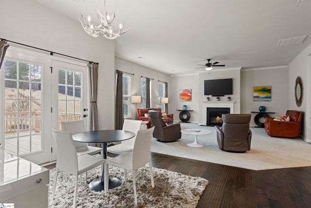 dining area with dark hardwood / wood-style flooring, ceiling fan with notable chandelier, ornamental molding, and a healthy amount of sunlight