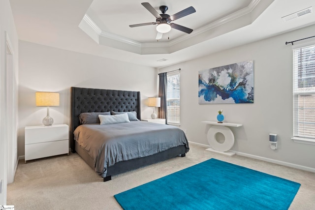 carpeted bedroom with ceiling fan, ornamental molding, and a raised ceiling