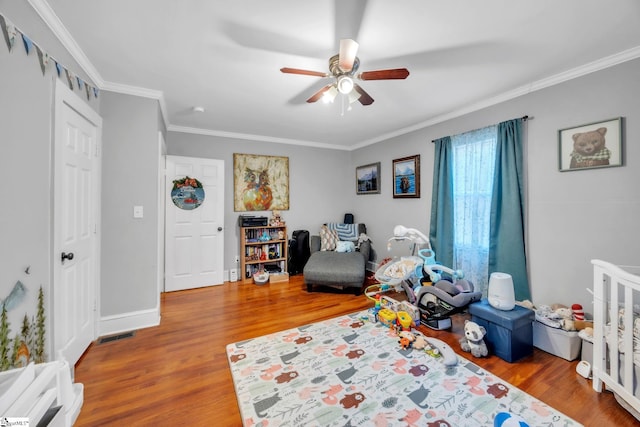 game room with hardwood / wood-style flooring, ornamental molding, and ceiling fan