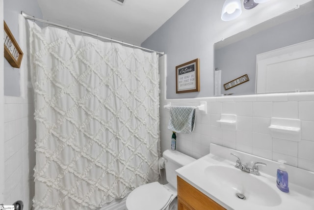 bathroom with vanity, tile walls, and toilet