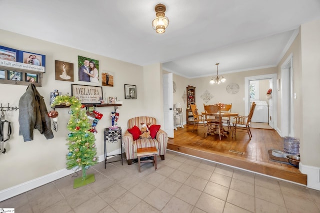 living area with crown molding, washer / clothes dryer, and a notable chandelier