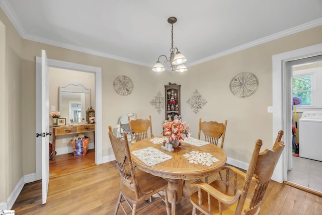 dining room featuring washer / clothes dryer, crown molding, an inviting chandelier, and light wood-type flooring