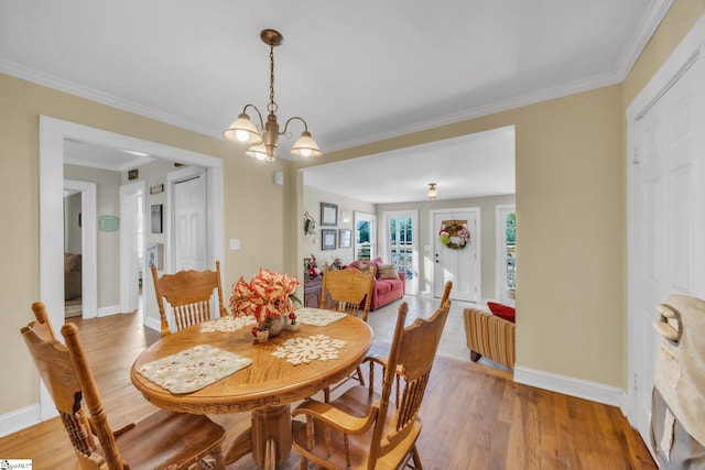 dining area with crown molding, wood-type flooring, and a chandelier