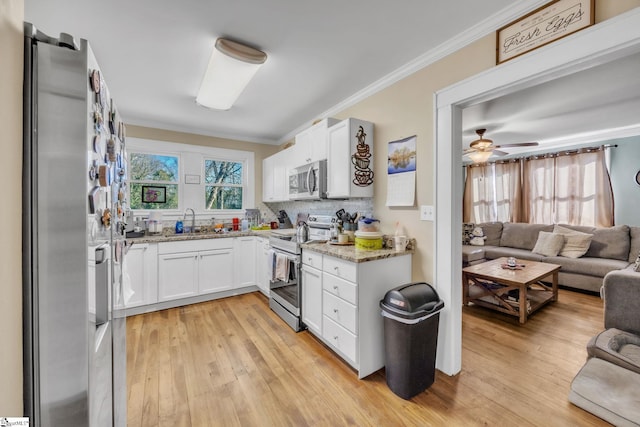 kitchen with sink, light stone counters, light wood-type flooring, stainless steel appliances, and white cabinets