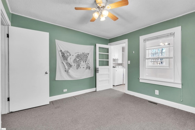 unfurnished bedroom featuring washer and dryer, carpet flooring, a textured ceiling, and ceiling fan