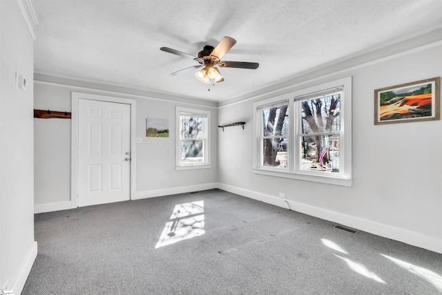 carpeted empty room with ceiling fan, ornamental molding, and a textured ceiling