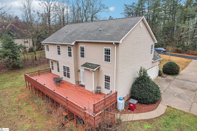 back of house with a fire pit, a wooden deck, and a garage