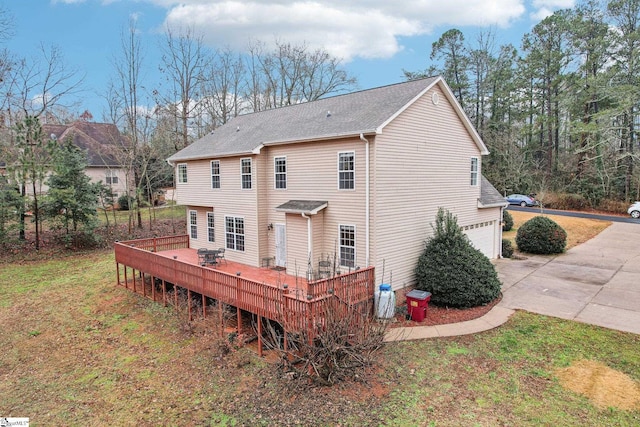 rear view of house featuring a garage, a yard, and a deck