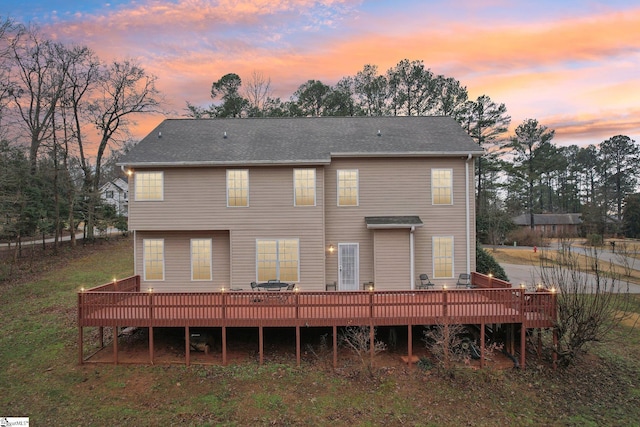 back house at dusk featuring a wooden deck