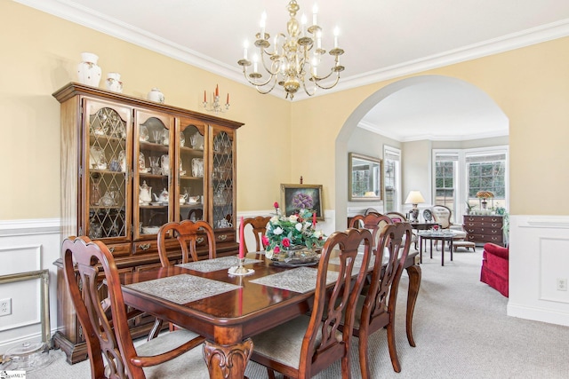 carpeted dining space with ornamental molding and a chandelier