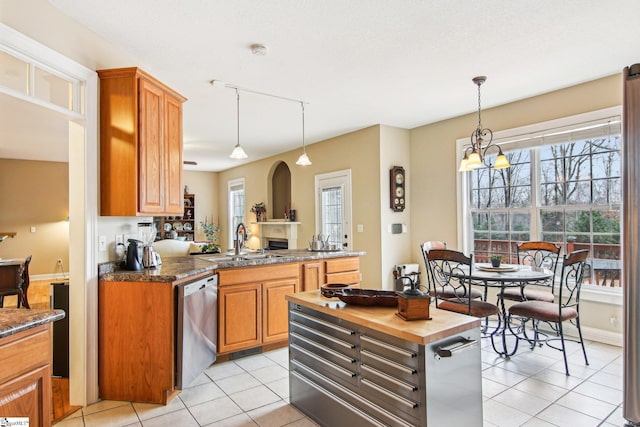 kitchen with hanging light fixtures, sink, stainless steel dishwasher, and light tile patterned floors