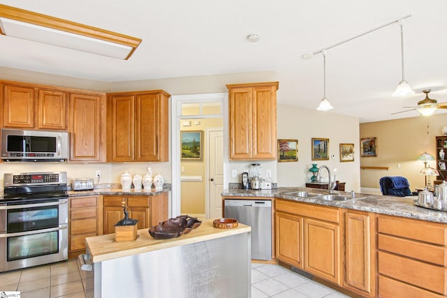 kitchen with sink, hanging light fixtures, light tile patterned floors, ceiling fan, and stainless steel appliances