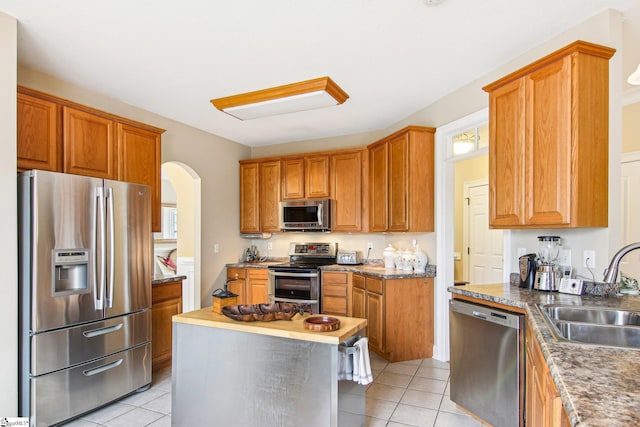 kitchen featuring sink, a kitchen island, stainless steel appliances, and light tile patterned flooring