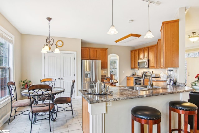 kitchen featuring decorative light fixtures, sink, light tile patterned floors, kitchen peninsula, and stainless steel appliances