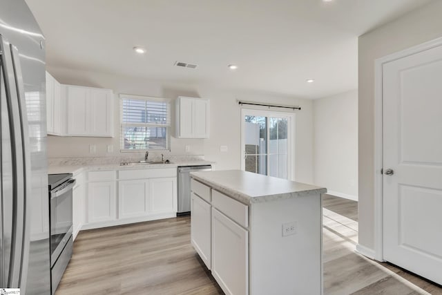 kitchen featuring stainless steel appliances, a center island, and white cabinets