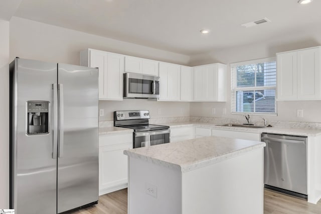 kitchen with sink, white cabinetry, a center island, light wood-type flooring, and stainless steel appliances