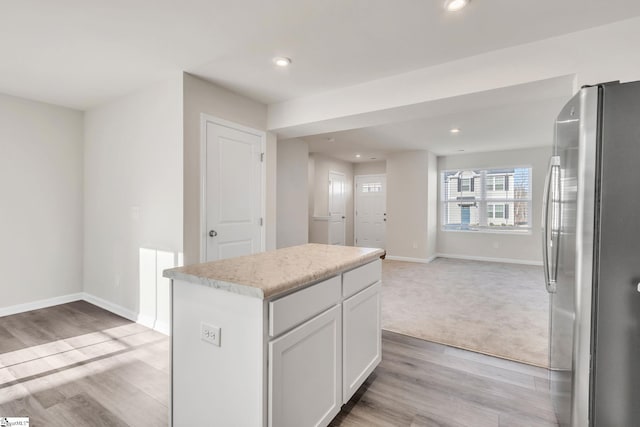 kitchen featuring a center island, white cabinets, stainless steel refrigerator, and light hardwood / wood-style floors