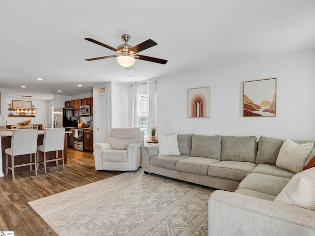 living room featuring dark wood-type flooring, sink, and ceiling fan