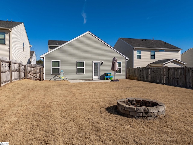 back of house featuring a yard, a patio, and a fire pit