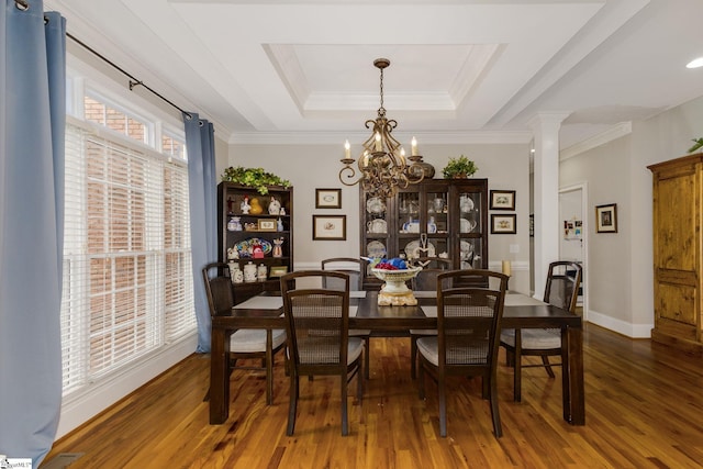 dining space with crown molding, decorative columns, dark hardwood / wood-style floors, a raised ceiling, and a chandelier