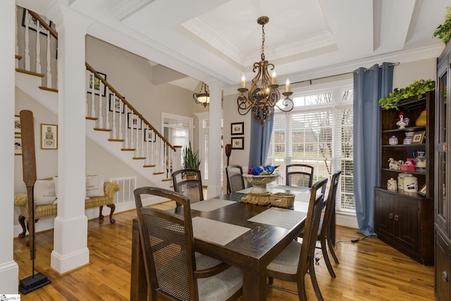 dining room featuring a raised ceiling, ornamental molding, hardwood / wood-style flooring, and a chandelier