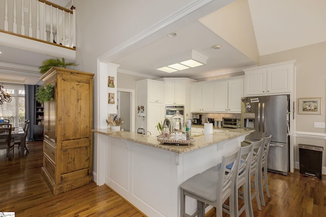 kitchen with white cabinetry, a breakfast bar area, light stone counters, stainless steel appliances, and crown molding