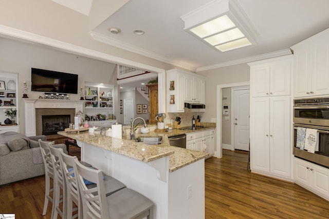 kitchen with appliances with stainless steel finishes, sink, white cabinets, a kitchen breakfast bar, and light stone countertops