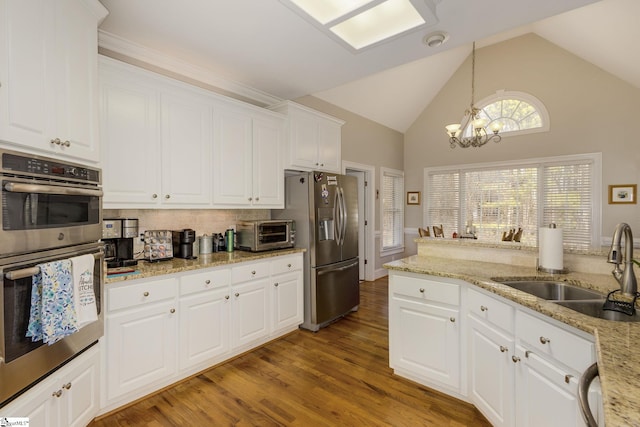 kitchen with stainless steel appliances, sink, white cabinets, and decorative light fixtures